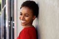 Smiling young black woman leaning against wall outside Royalty Free Stock Photo