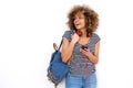 Smiling young black woman with mobile phone headphones and bag against white background