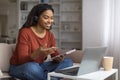 Smiling young black woman wearing headset engaging in virtual meeting on laptop Royalty Free Stock Photo