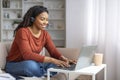 Smiling Young Black Woman Wearing Headset Using Laptop Computer At Home Royalty Free Stock Photo