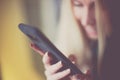 Smiling young blond woman use smartphone, soft selective focus on her fingers, blurred happy girl face Royalty Free Stock Photo