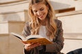Smiling young blonde casual woman reading book Royalty Free Stock Photo