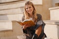 Smiling young blonde casual woman reading book Royalty Free Stock Photo