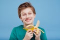 Smiling young boy with a banana in his handin green t-shirt Royalty Free Stock Photo