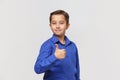 Smiling young boy in blue classic shirt shows thumbs up Royalty Free Stock Photo