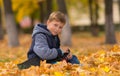 Smiling young boy sitting in park with skateboard. Royalty Free Stock Photo