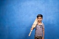 Smiling young boy kid holding cricket bat by looking at camera - concept of future goal, inspiration, childhood dream