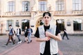 A smiling young boy with a notepad in his hands stands against the background of the university and college students. Royalty Free Stock Photo