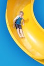 Smiling Young boy riding down a yellow water slide Royalty Free Stock Photo