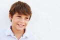 Smiling Young Boy Standing Outdoors Against White Wall Royalty Free Stock Photo