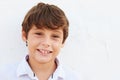 Smiling Young Boy Standing Outdoors Against White Wall Royalty Free Stock Photo