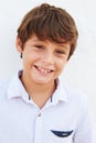 Smiling Young Boy Standing Outdoors Against White Wall Royalty Free Stock Photo