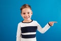 Smiling young boy in sweater pointing away Royalty Free Stock Photo