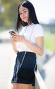 Smiling young brazilian girl chatting on smartphone in city street Royalty Free Stock Photo