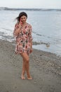 Smiling young brunette caucasian woman chatting on a red mobile phone in the beach. People lifestyle concept Royalty Free Stock Photo