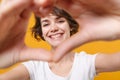 Smiling young brunette woman girl in white t-shirt posing isolated on yellow orange background in studio. People Royalty Free Stock Photo