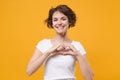 Smiling young brunette woman girl in white t-shirt posing isolated on yellow orange background in studio. People Royalty Free Stock Photo