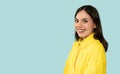 Smiling confident young brunette woman side-profile portrait at blue background with copy space