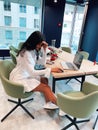 Smiling young brunette woman sitting at bright modern office space and working on laptop Royalty Free Stock Photo