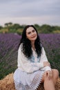 Young woman sitting on hay bale among blooming lavender Royalty Free Stock Photo