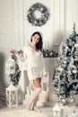 Smiling young brunette woman standing near fir tree in Christmas Royalty Free Stock Photo