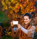 Woman taking photo with mobile while relaxing in autumn park Royalty Free Stock Photo