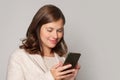 Smiling young brunette woman using mobile phone, typing sms message, portrait Royalty Free Stock Photo