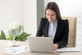 Smiling young business lady working with laptop, looking at scre