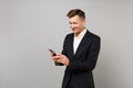 Smiling young business man in classic black suit with wireless earphones listening music using mobile phone isolated on Royalty Free Stock Photo