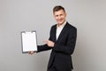 Smiling young business man in suit pointing index finger on clipboard with blank empty sheet workspace isolated on grey Royalty Free Stock Photo