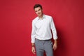 Smiling young business man in white shirt, gray pants posing isolated on bright red wall background studio portrait Royalty Free Stock Photo