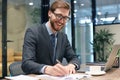 Smiling young business man writing something down while working in modern office Royalty Free Stock Photo