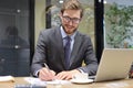 Smiling young business man writing something down while working in modern office Royalty Free Stock Photo