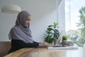 Smiling young business woman in hijab working with laptop in bright modern office Royalty Free Stock Photo