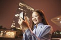 Smiling young business woman looking at her mobile phone outside at night Royalty Free Stock Photo