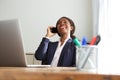 Smiling young business woman sitting at office desk and talking on cell phone Royalty Free Stock Photo