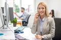 Smiling young business woman talking on mobile phone while sitting in office. Royalty Free Stock Photo