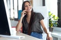 Smiling young business woman talking on mobile phone while sitting in the office Royalty Free Stock Photo