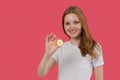 Smiling young business woman in white shirt holding bitcoin in hand posing