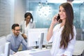 Smiling young business woman talking on mobile phone in office Royalty Free Stock Photo