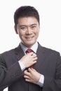 Smiling young businessman adjusting his tie, studio shot Royalty Free Stock Photo