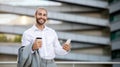 Smiling young businessman with coffee and phone posing outdoors Royalty Free Stock Photo