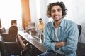 smiling young businessman with crossed hands looking at camera and his partners working behind at modern Royalty Free Stock Photo