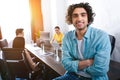 smiling young businessman with crossed hands looking at camera and his partners working behind at modern Royalty Free Stock Photo