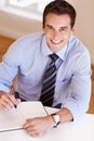 Things are looking busy - Scheduling. Smiling young businessman filling in his dayplanner. Royalty Free Stock Photo