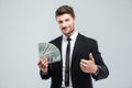 Smiling young businessman holding money and showing thumbs up Royalty Free Stock Photo