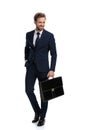 Smiling young businessman in navy blue suit holding suitcase Royalty Free Stock Photo