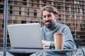 Smiling young businessman using laptop to work remotely from coffee terrace, Portrait of successful freelancer or Royalty Free Stock Photo