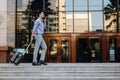 Smiling  Young Businessman Using Mobile Phone while Walking with Suitcase in the City. Lifestyle of Modern People Royalty Free Stock Photo