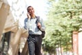 Smiling young businessman walking and talking with mobile phone Royalty Free Stock Photo